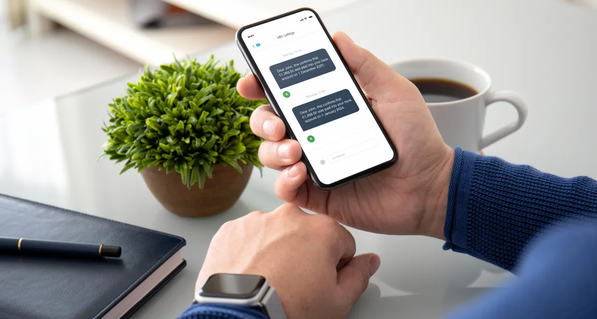 A person holding a phone with a payment notification message displayed on the screen