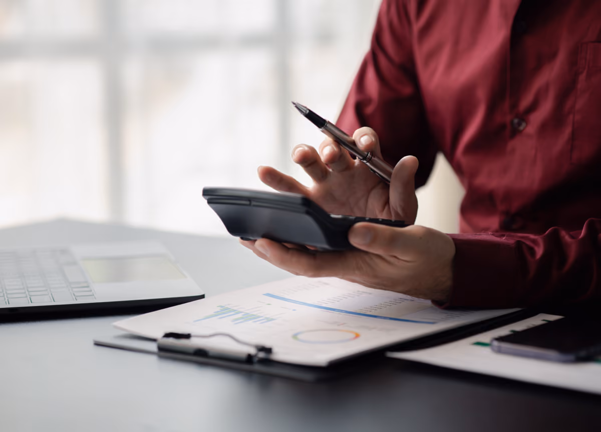 A man reviews his financial documents with pen and calculator in hand