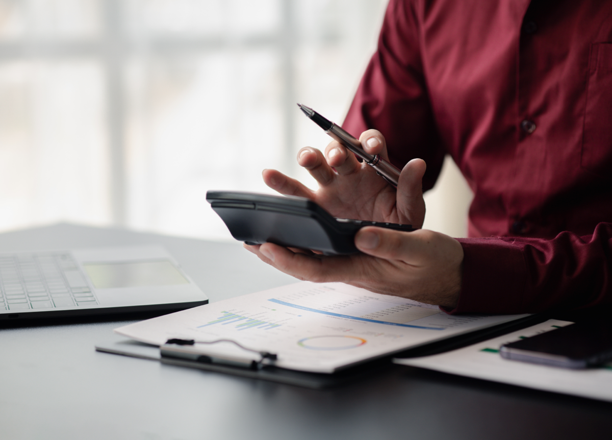 A man reviews his financial documents with pen and calculator in hand