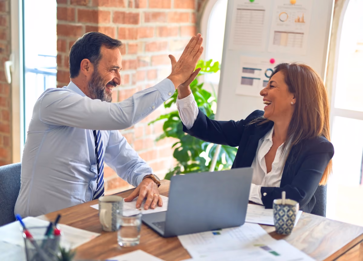 Male and female office workers smiling and giving each other a high-five