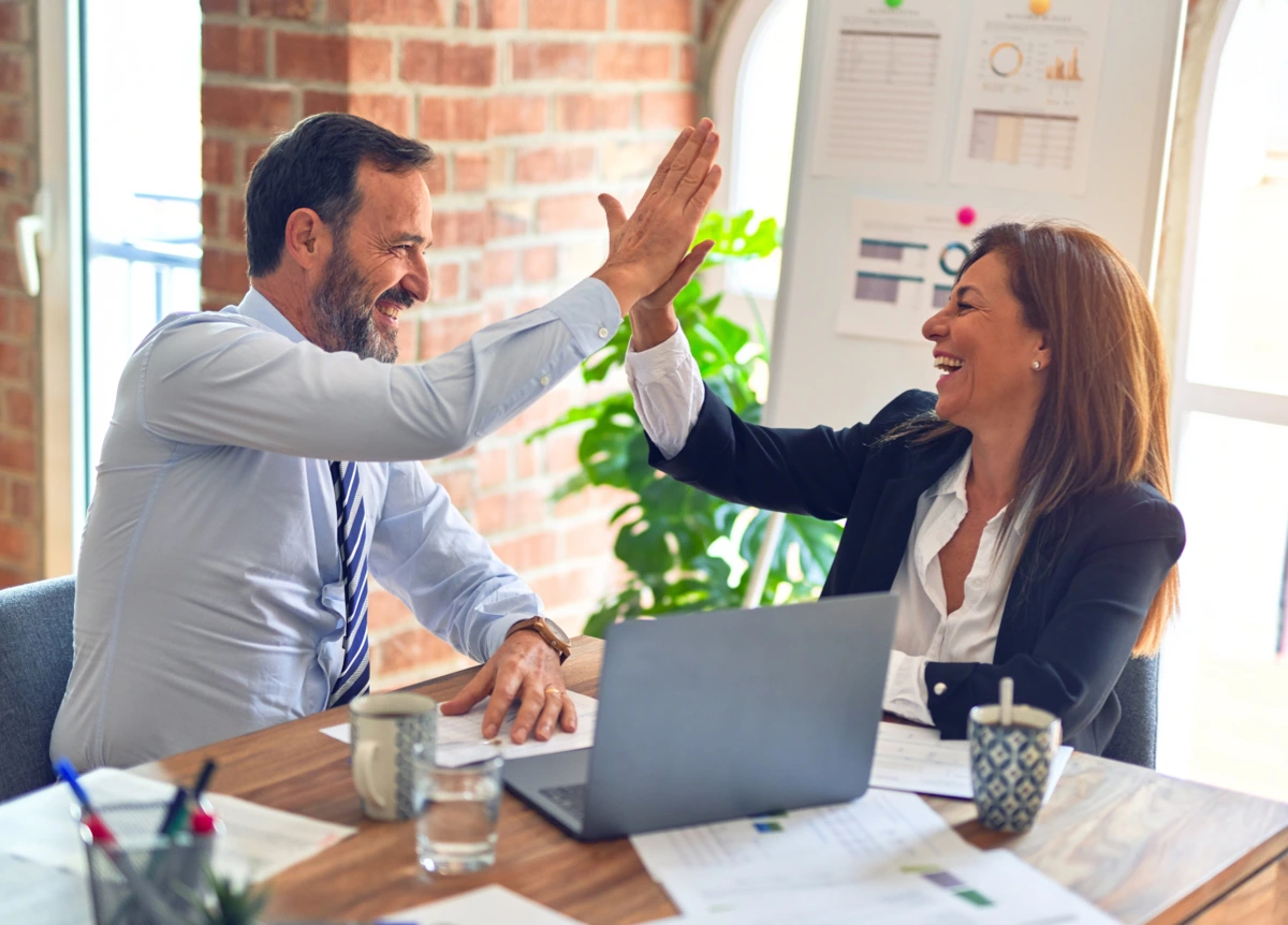 Male and female office workers smiling and giving each other a high-five
