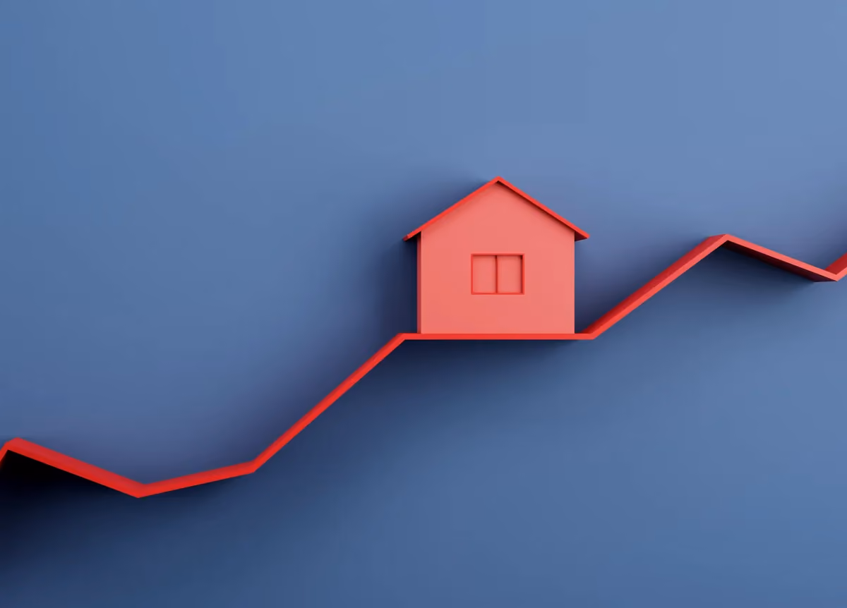 A red model house sitting on a rising graph line