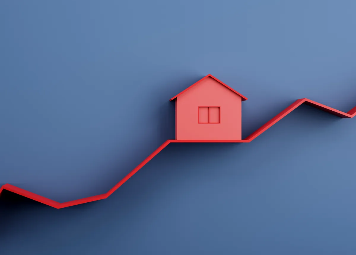 A red model house sitting on a rising graph line