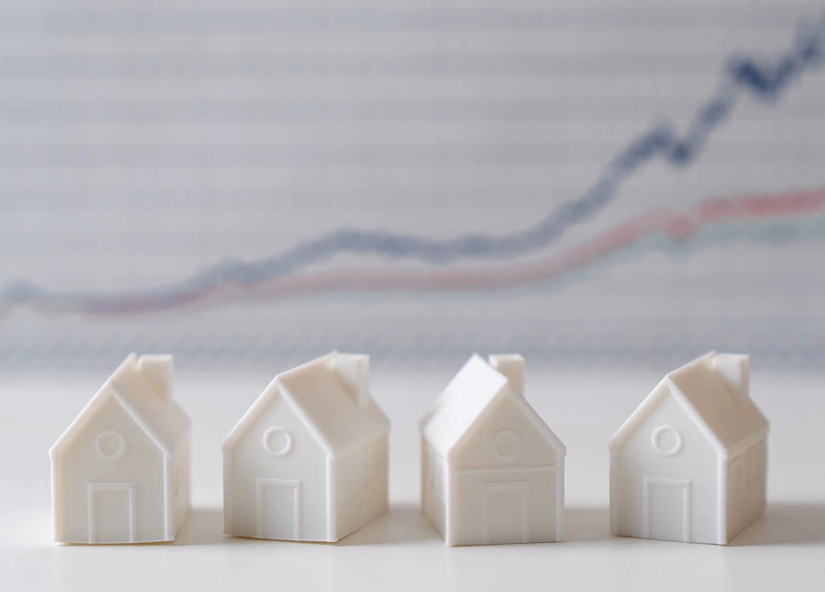 White miniature house models with graph in the background indicating prices are rising