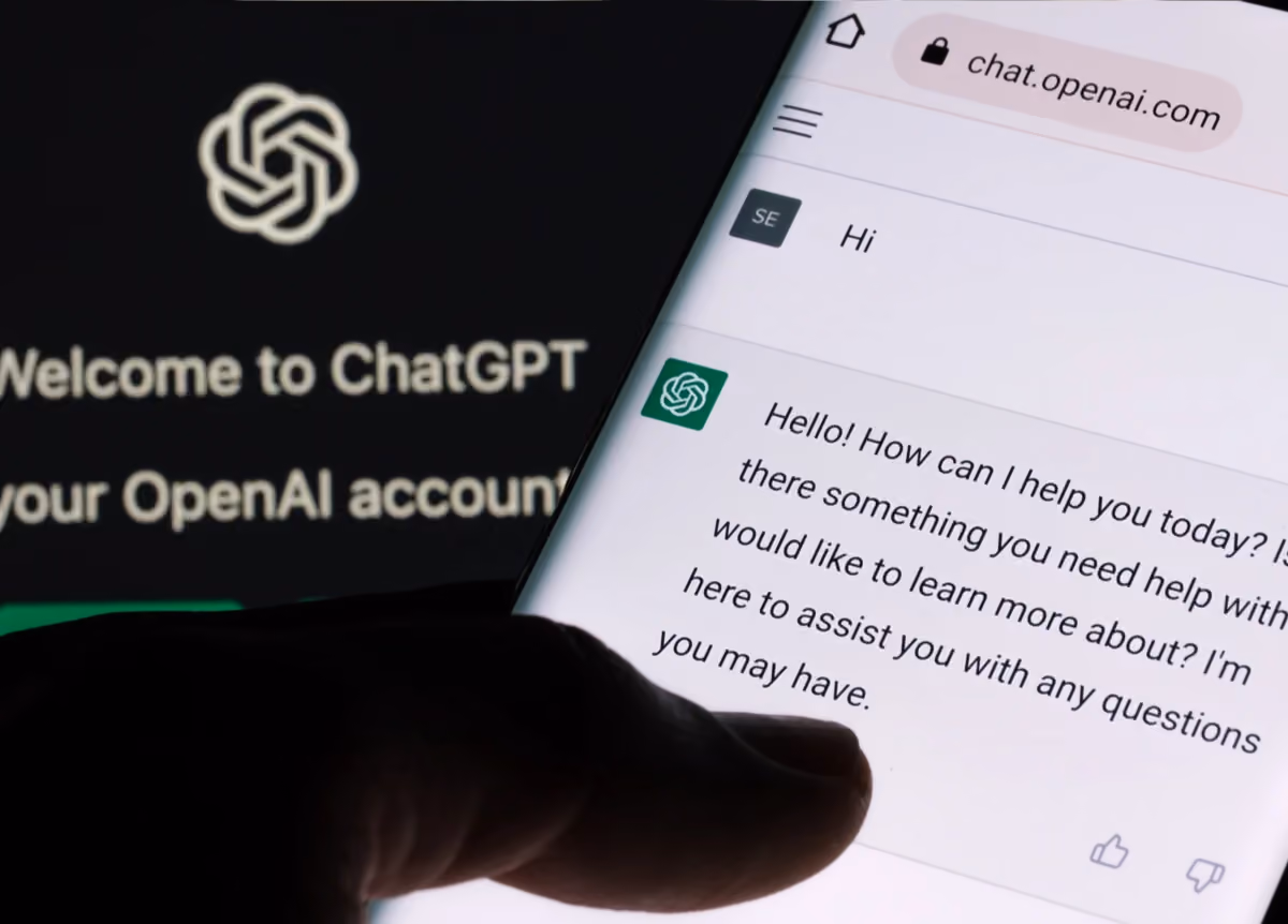 Close-up of ChatGPT chatbot on smartphone and laptop display with ChatGPT login screen on the background