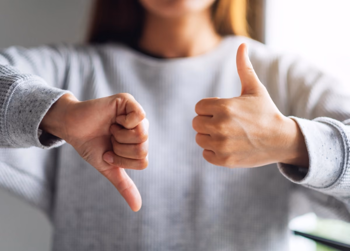 Woman holds one thumb up and one thumb down