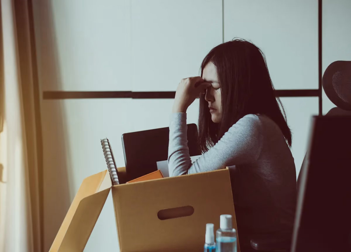 Stressed woman holds cardboard box of personal belongings