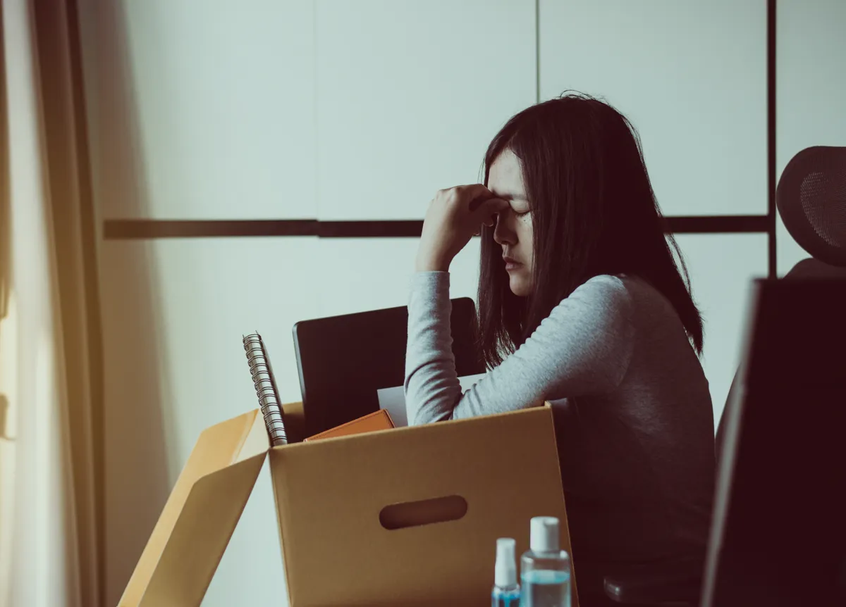 Stressed woman holds cardboard box of personal belongings