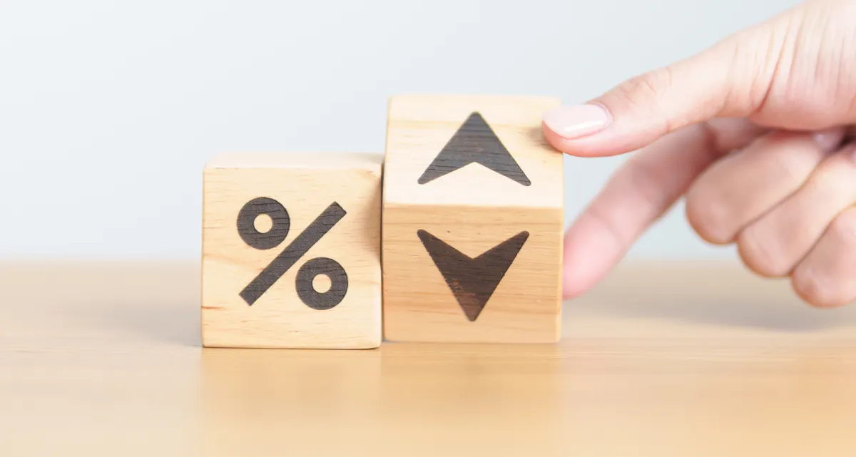 Two wooden blocks, one with a percentage symbol and the other with arrows pointing up and down