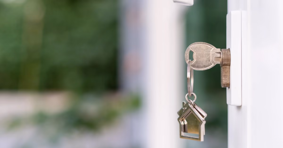 A key with a house shaped keychain in a door