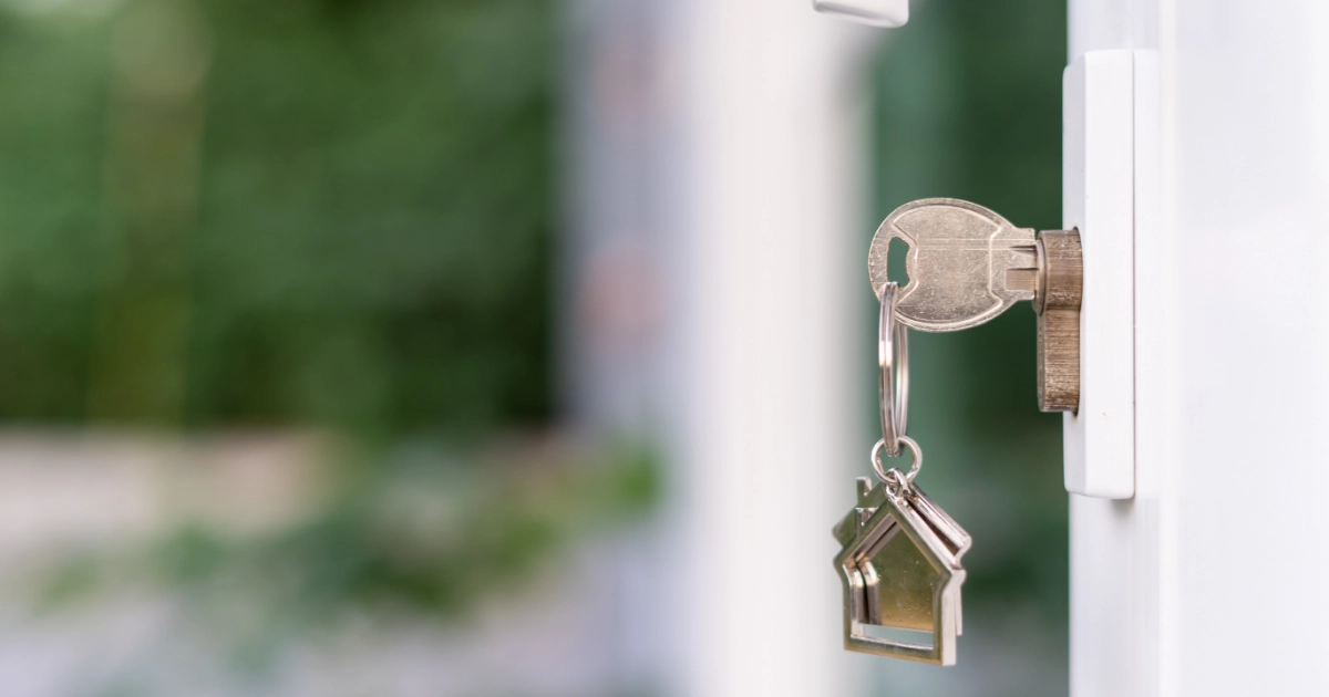 A key with a house shaped keychain in a door