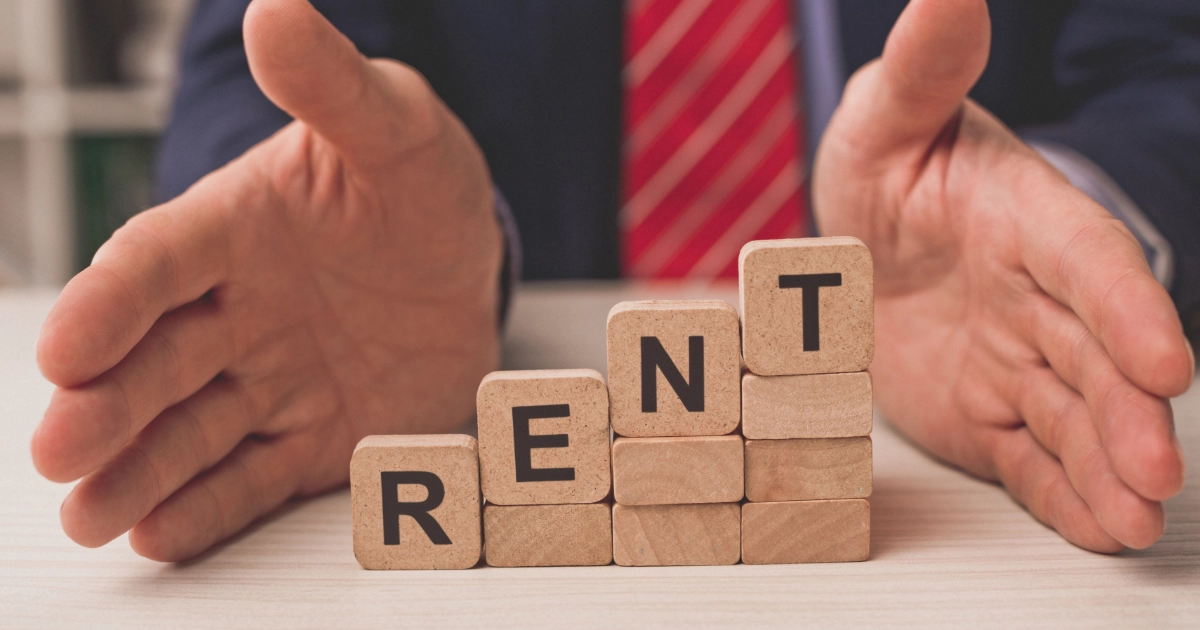 Four wooden letter blocks stepping up, reading "RENT"