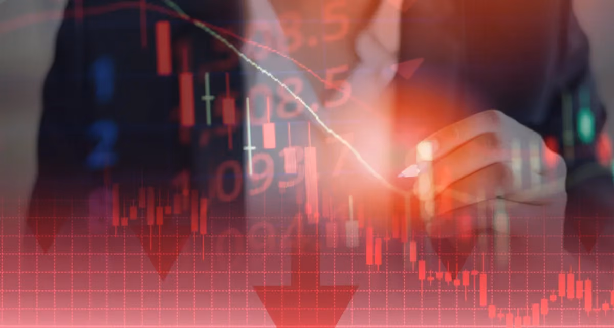 A man in a suit behind a transparent red screen of graphs with a falling trend line