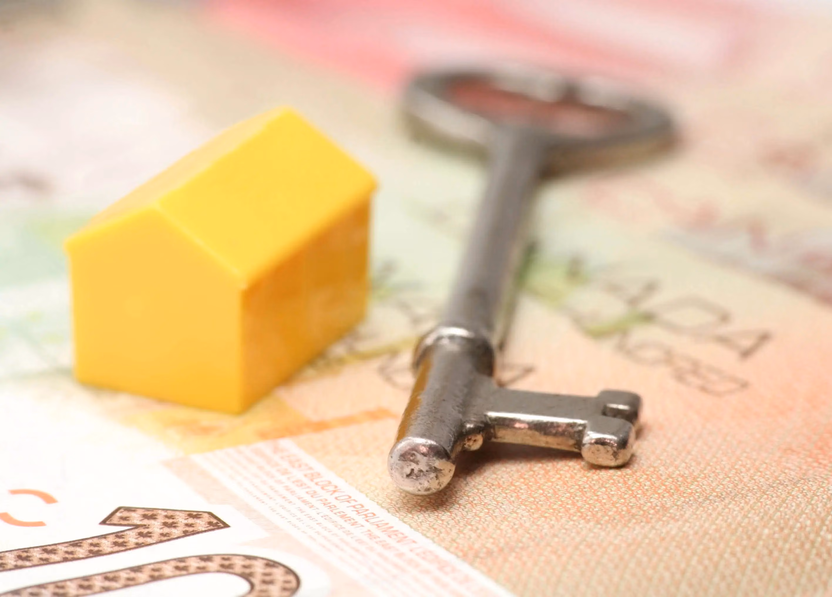 Model of house and key sitting atop Canadian money