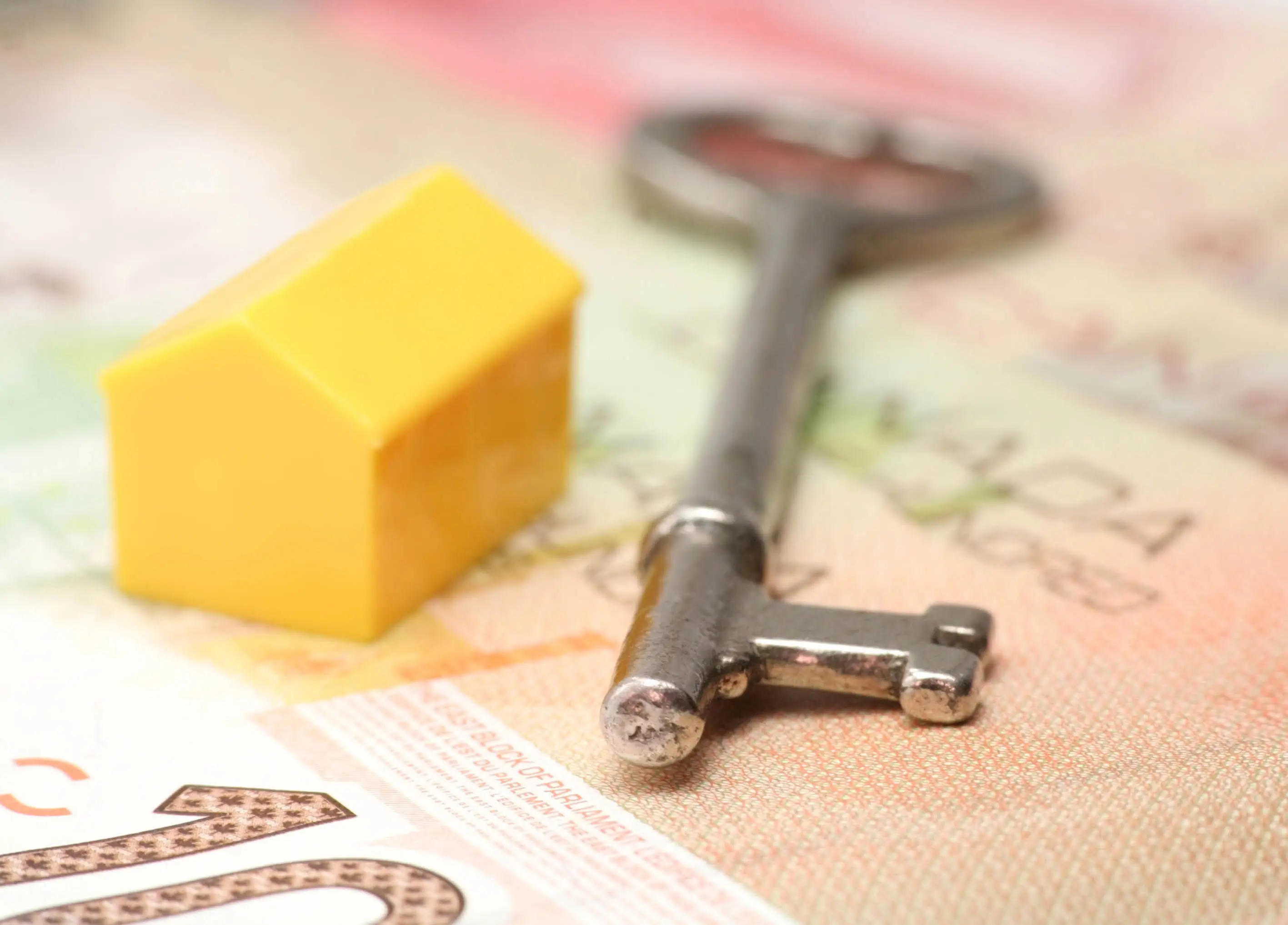 Model of house and key sitting atop Canadian money