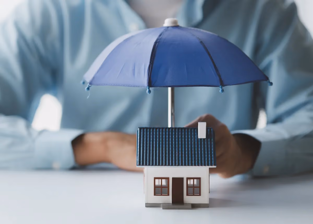 Model of house protected by umbrella