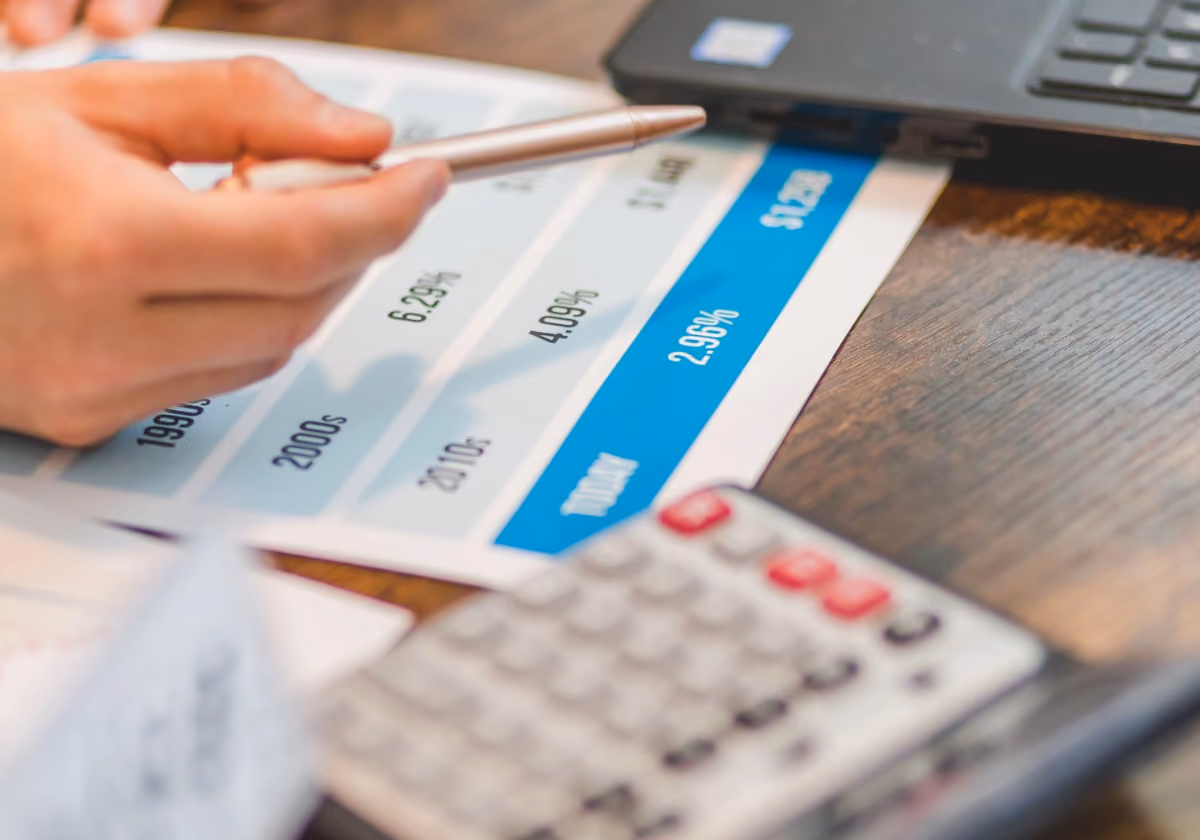 Person pointing at graph of interest rates on desk