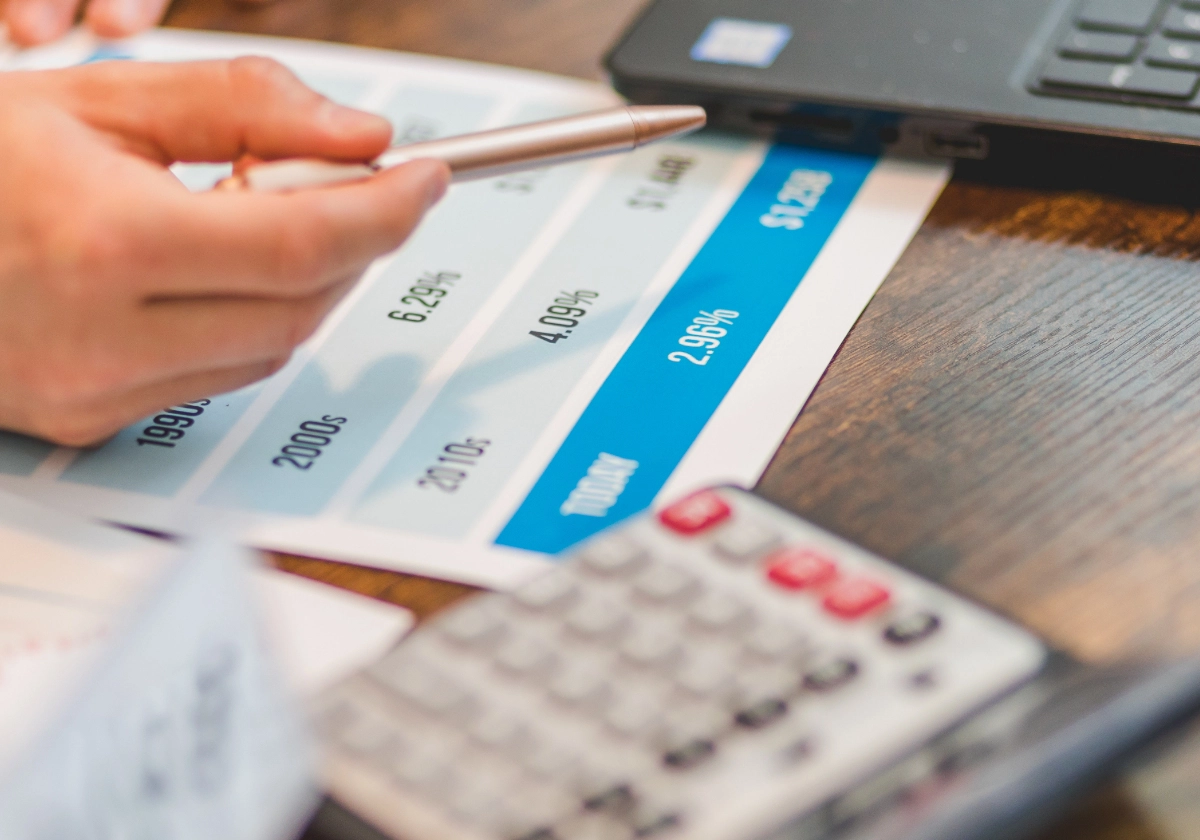 Person pointing at graph of interest rates on desk