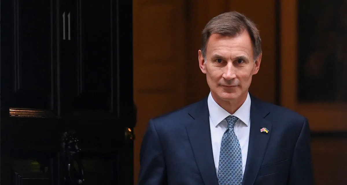 UK Chancellor Jeremy Hunt shown standing in front of a door