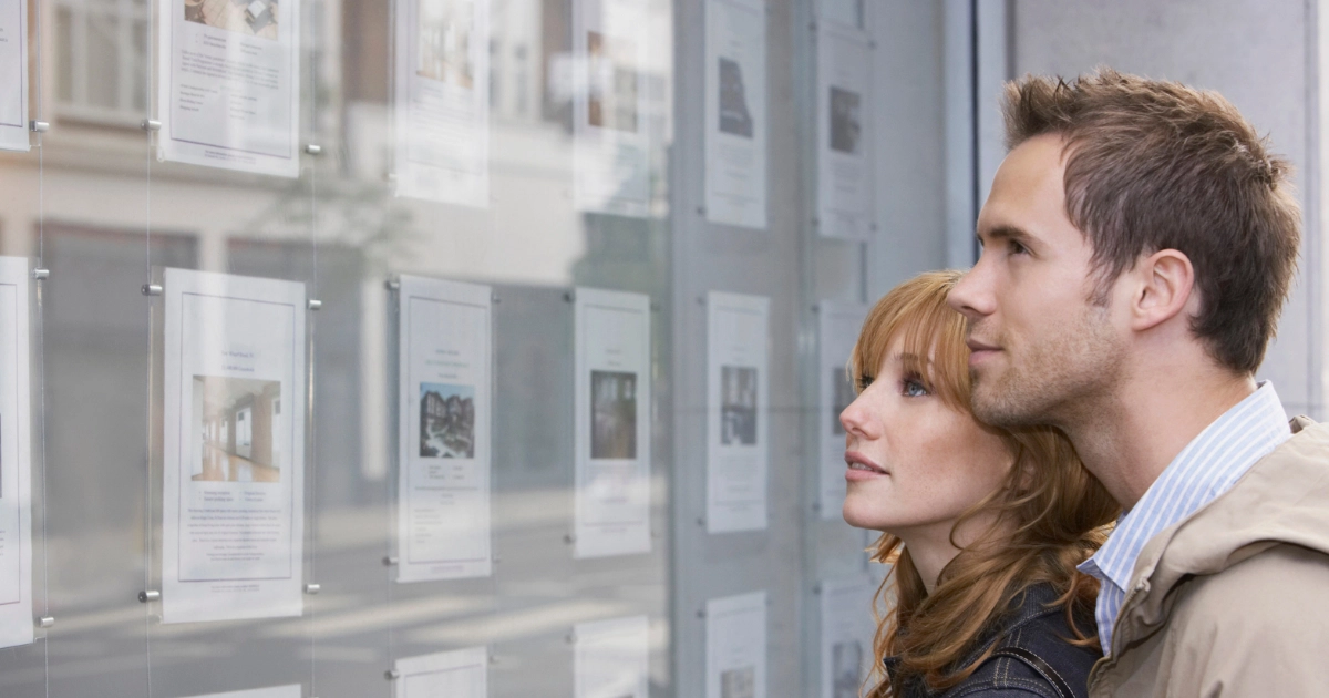 A man and a woman looking at listings in an estate agent's window