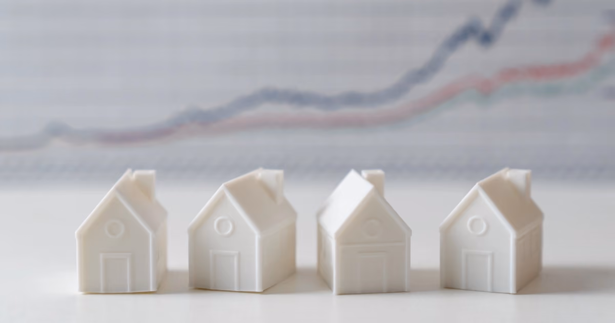 Four small model houses in front of a graph