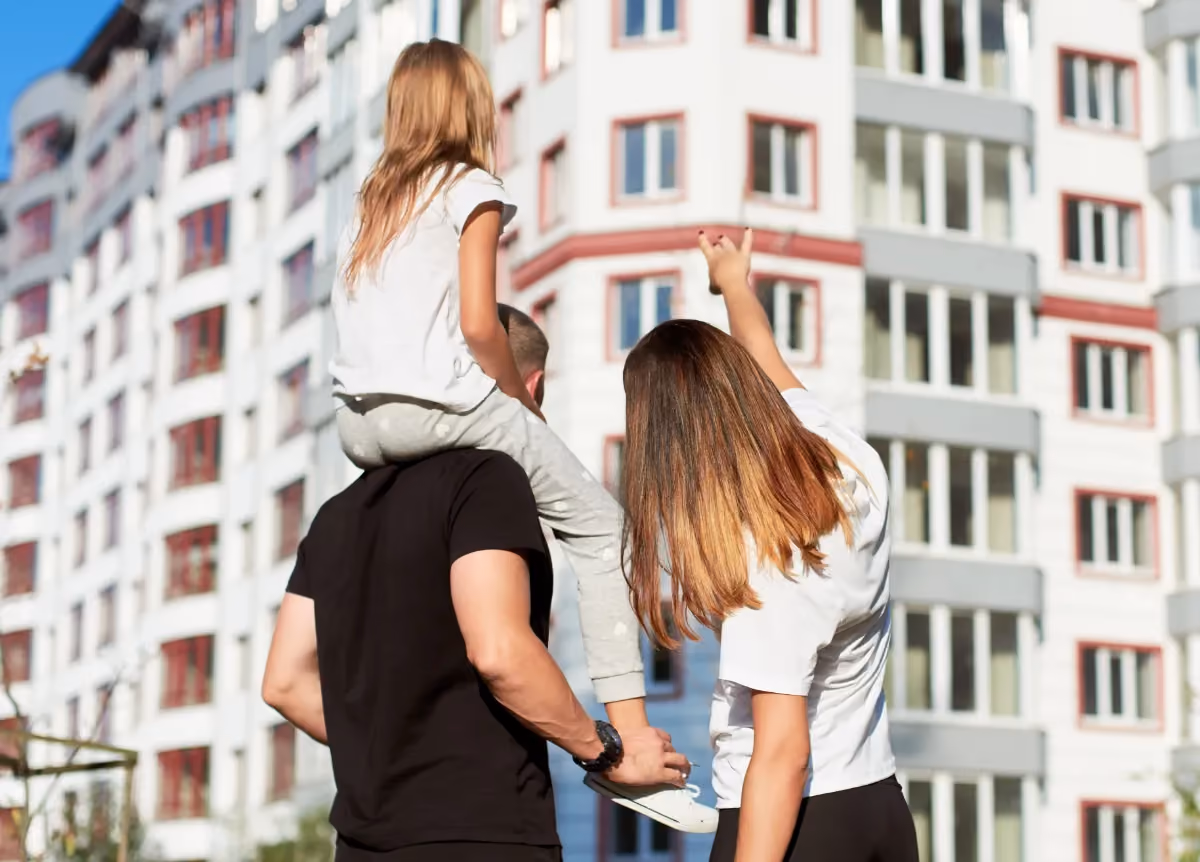 Family of three looking up at new apartment building
