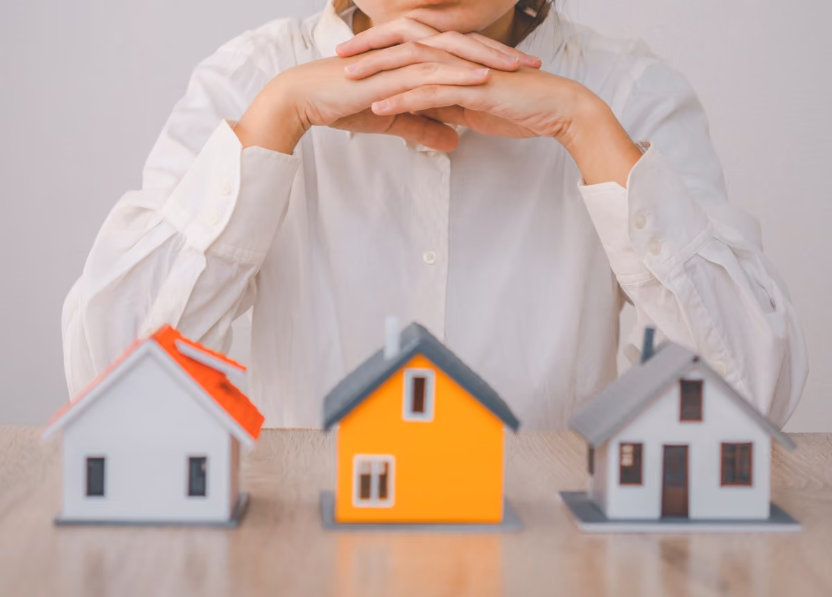 Woman observing three little wooden models of houses