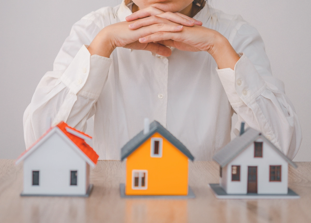 Woman observing three little wooden models of houses