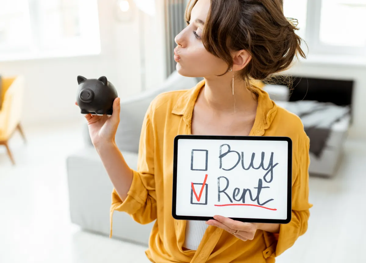 Woman holds piggy bank and sign asking whether to buy or rent