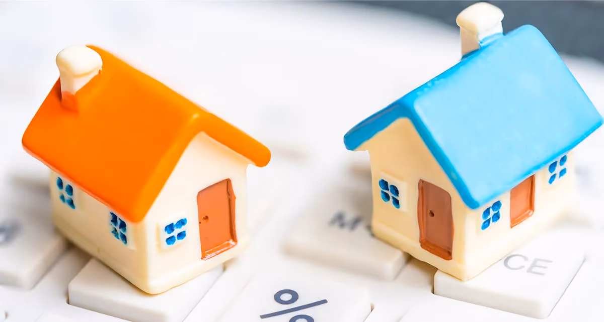 2 miniature model houses on a calculator keyboard with the percent sign clearly visible