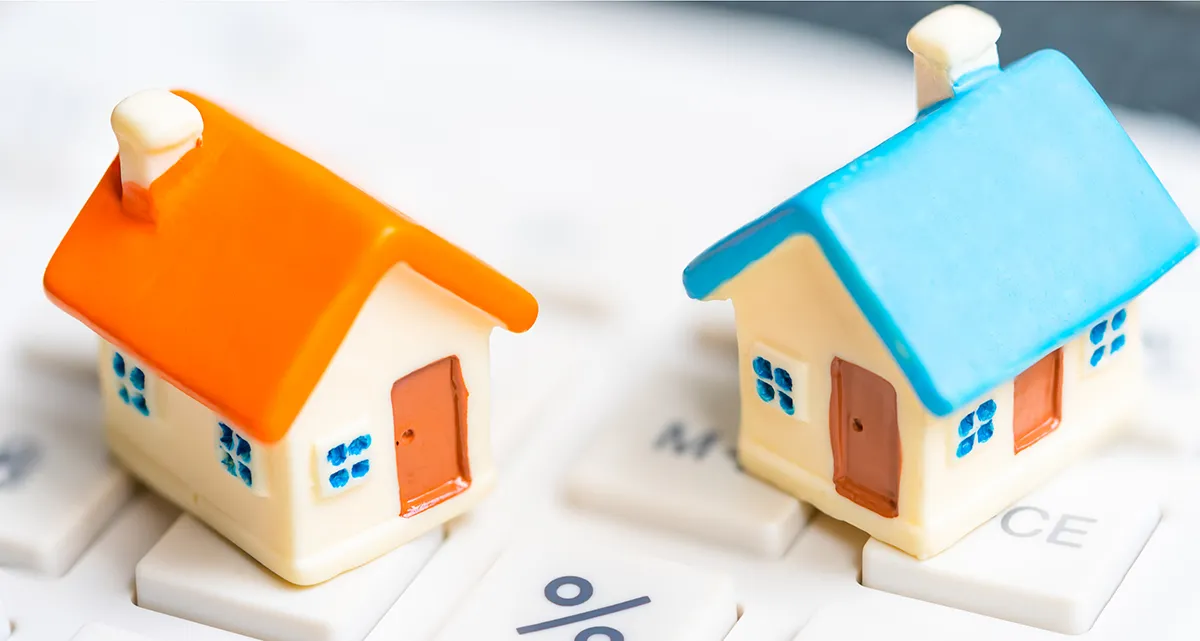 2 miniature model houses on a calculator keyboard with the percent sign clearly visible