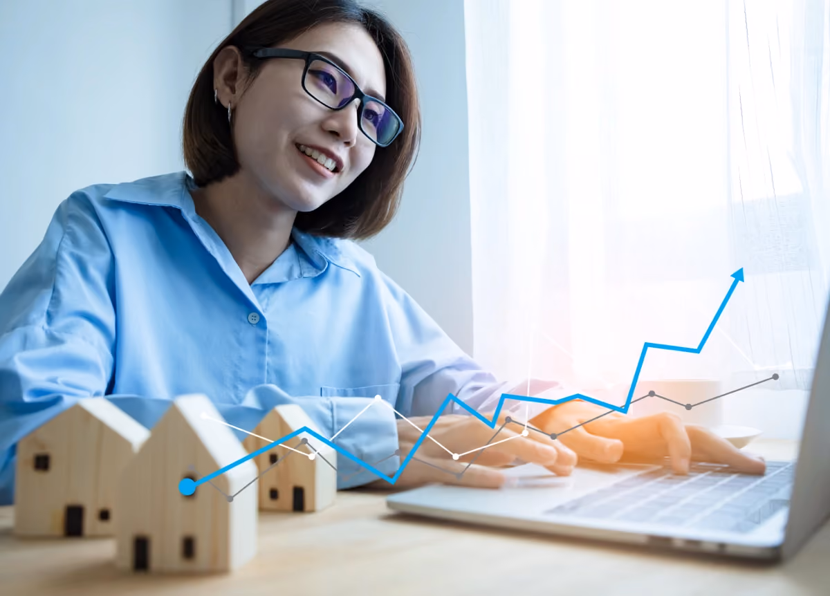 Upward-trending line graphs overlayed on top of a young woman on a laptop