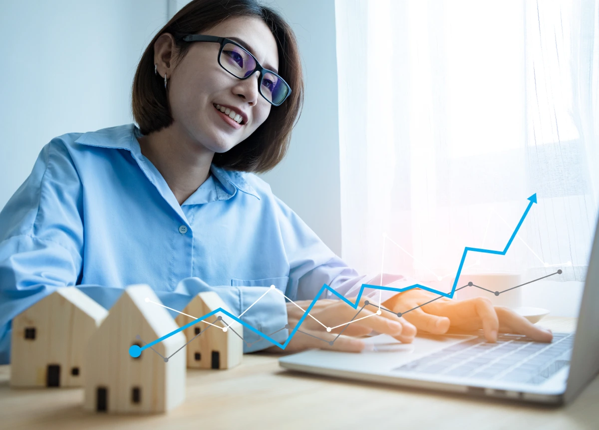 Upward-trending line graphs overlayed on top of a young woman on a laptop