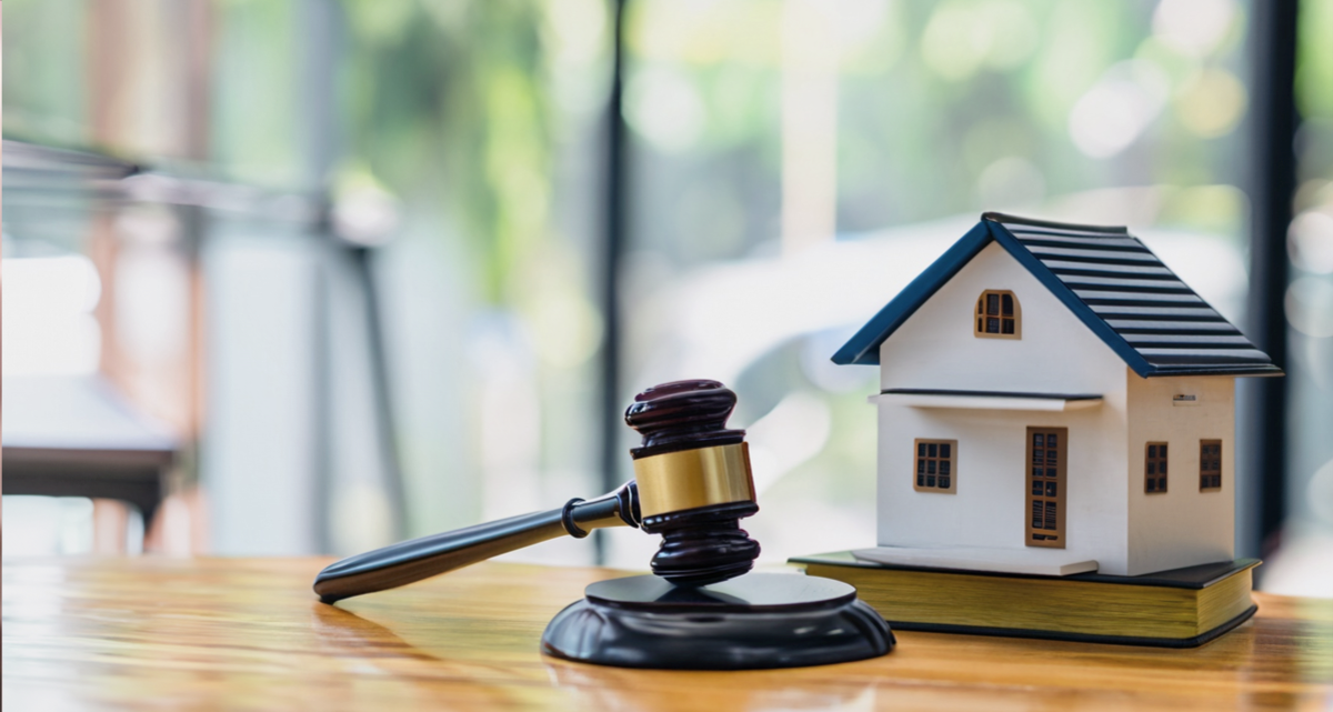 A model house and a gavel on a table