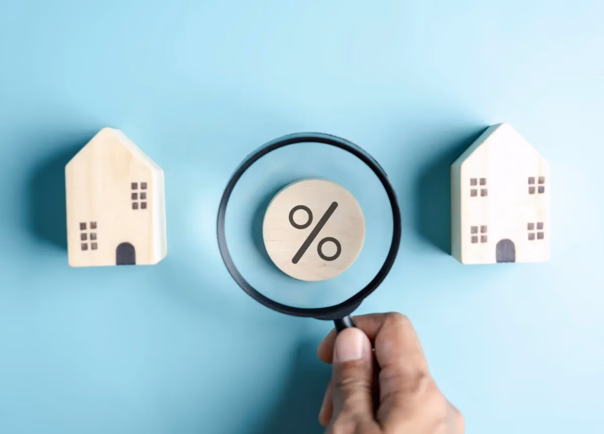 A magnifying glass over a percentage sign between two model houses