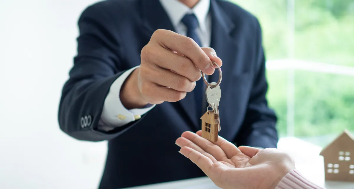 A man in a suit handing someone a set of keys