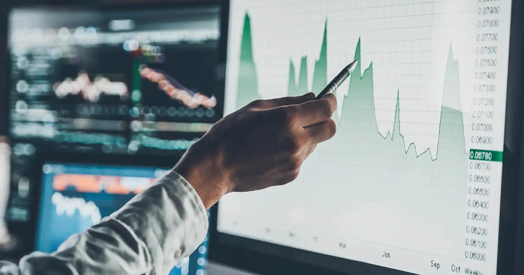 A man's hand using a pen to point at a graph on a computer screen