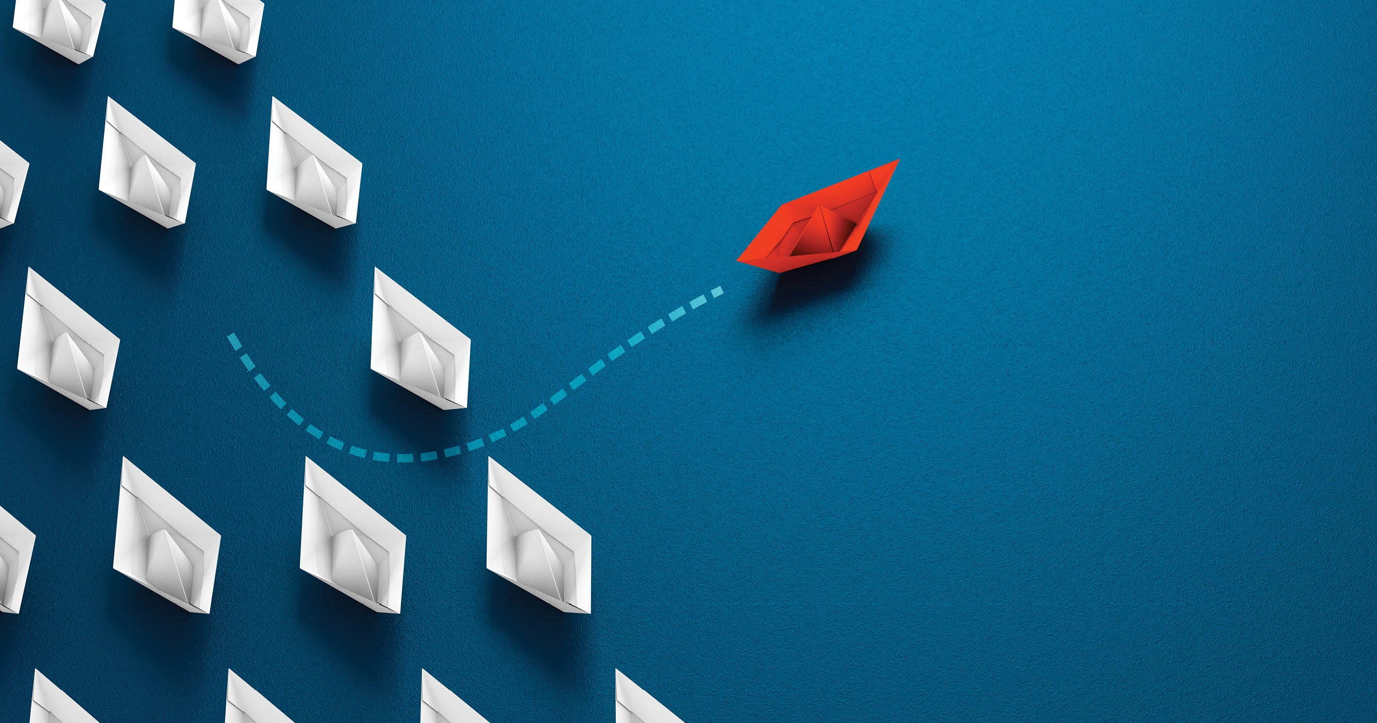 A red paper boat sailing away from a group of white paper boats