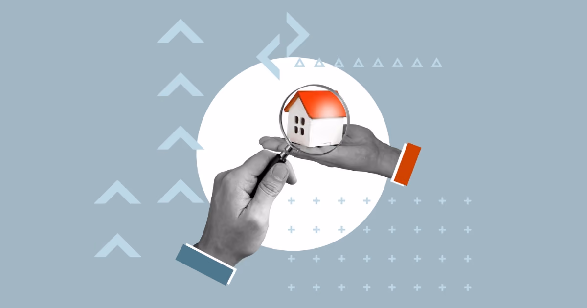 Two hands, one holding a model house and the other holding a magnifying glass