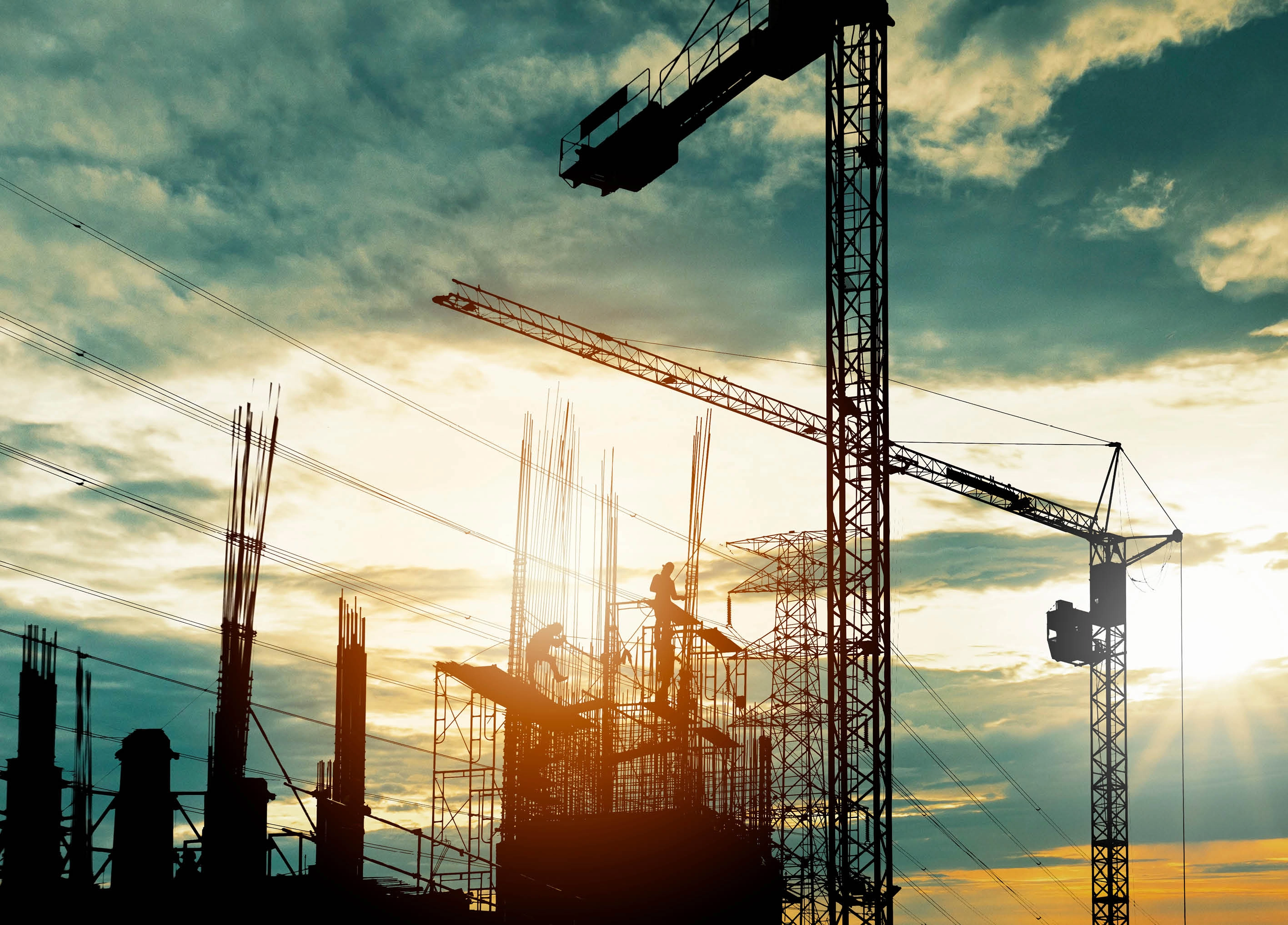 Silhouette of crane construction building towers at sunset