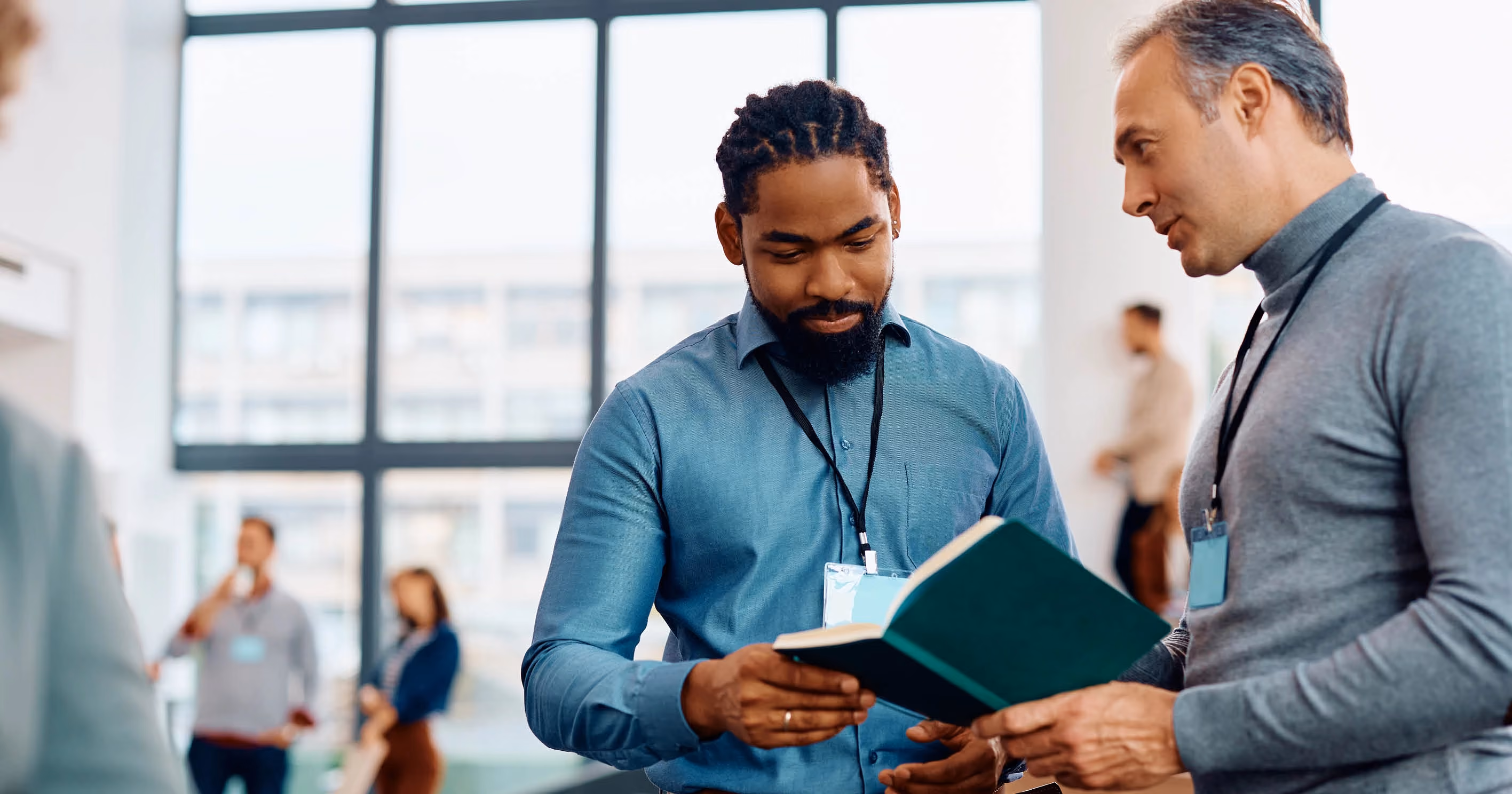Two men in professional clothing looking at a book