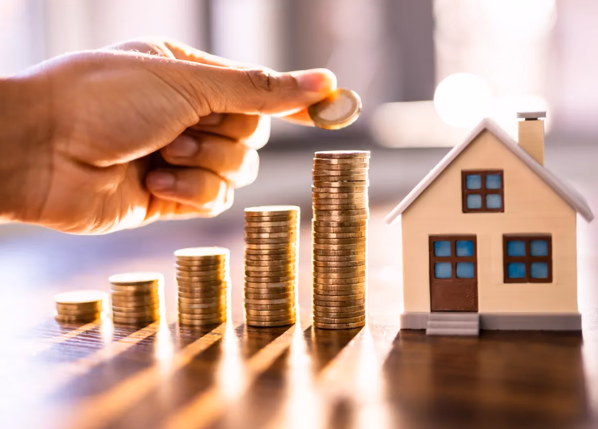Man places coins next to model of a house