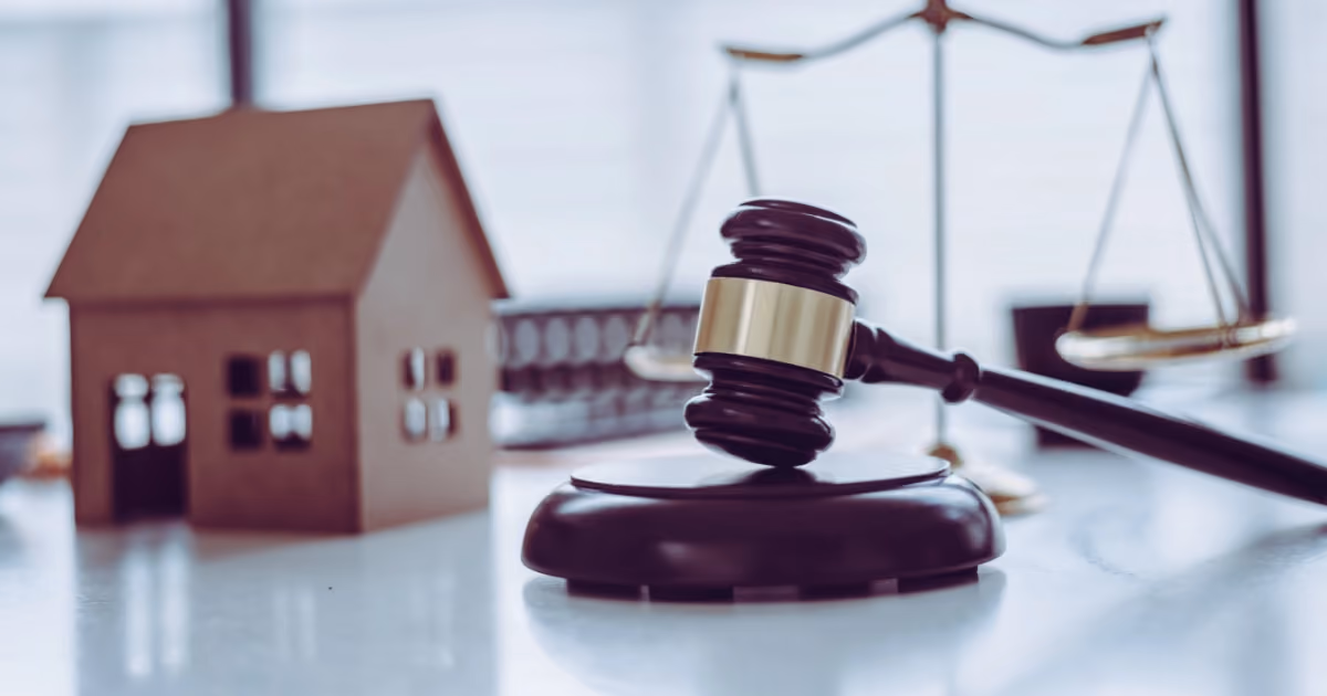 A gavel next to a model house