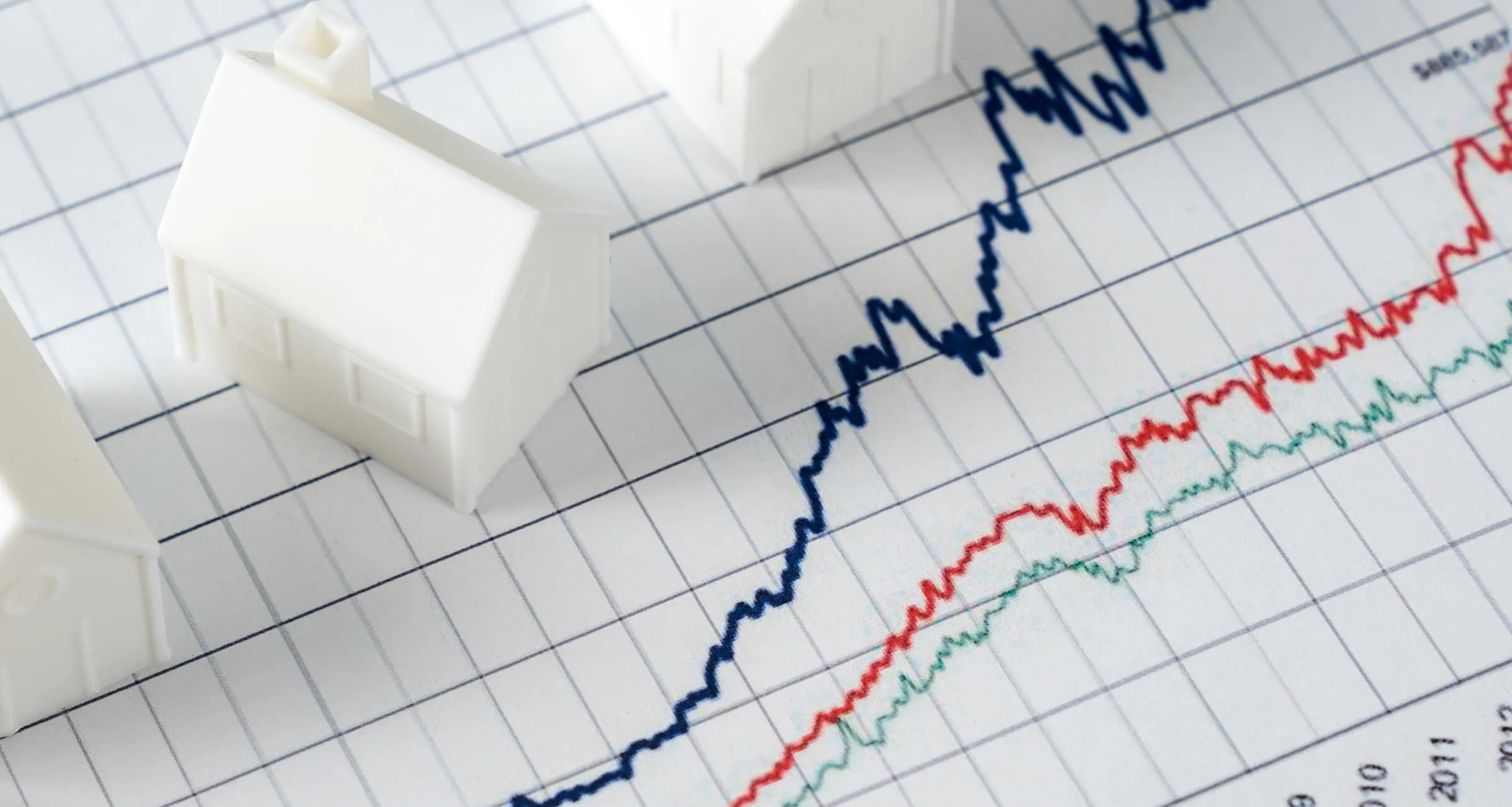 An image of a model house on a line graph chart on a desk