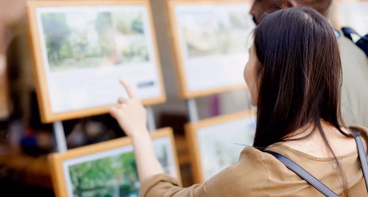 A woman pointing at a real estate listing in a window