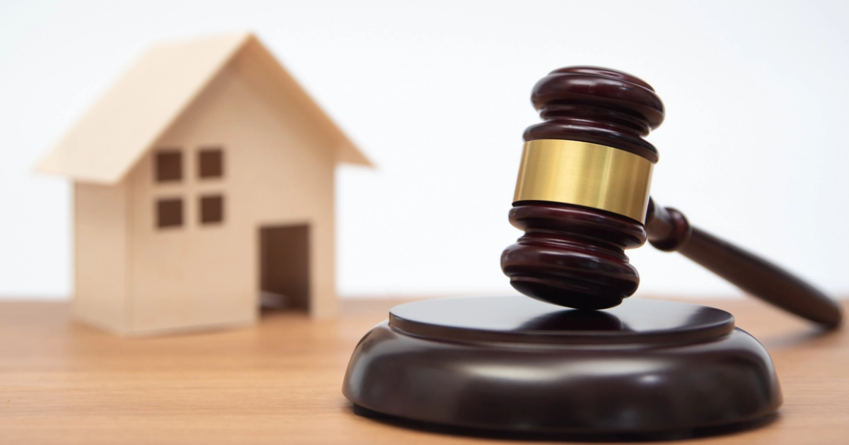 A gavel next to a model house