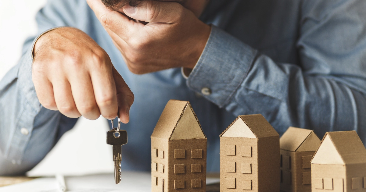 A man holding a set of keys looking down at a set of model houses
