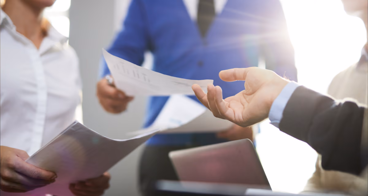 A person handing over a document to another person