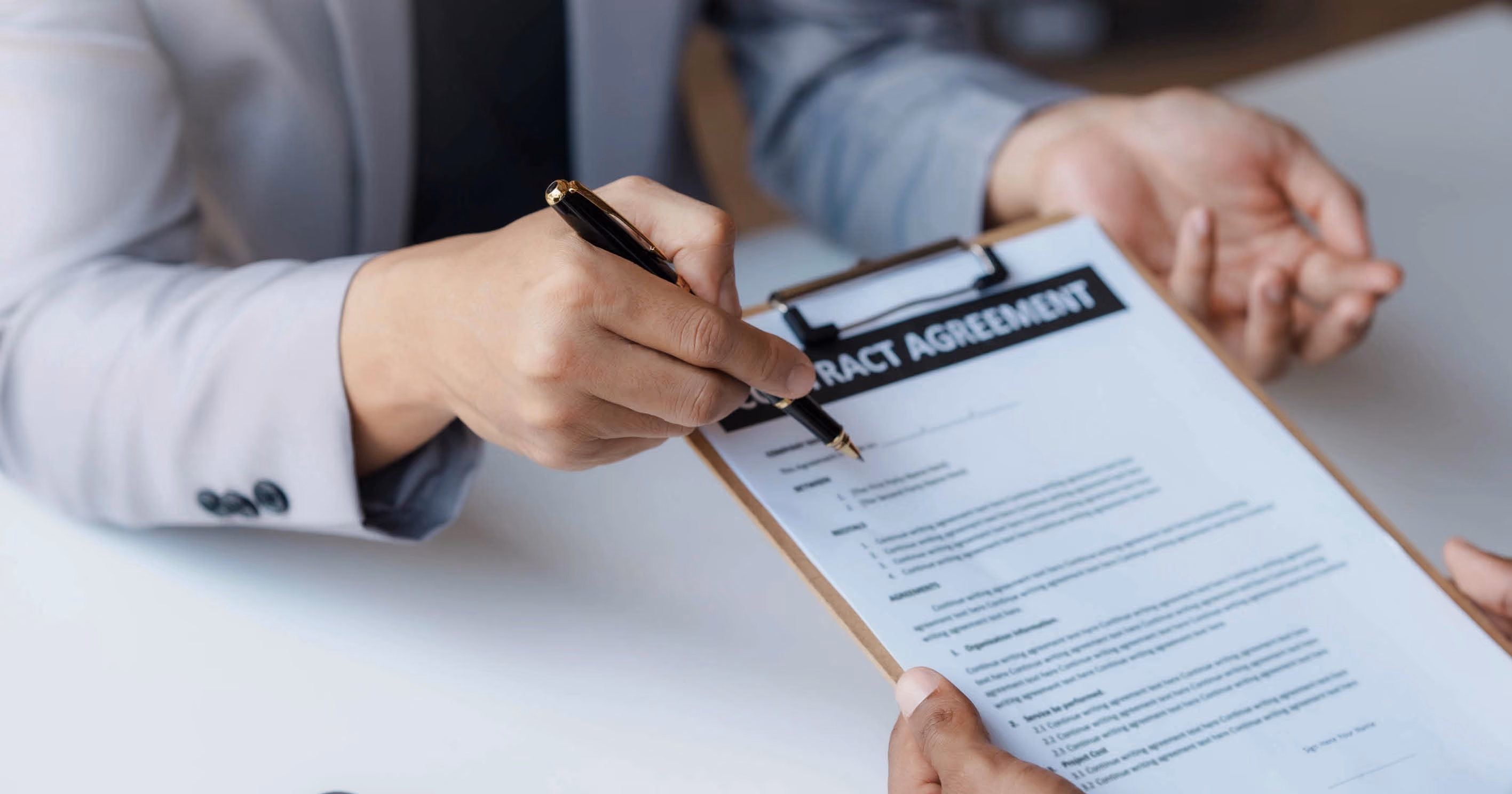 A person holding out a tenancy agreement on a clipboard