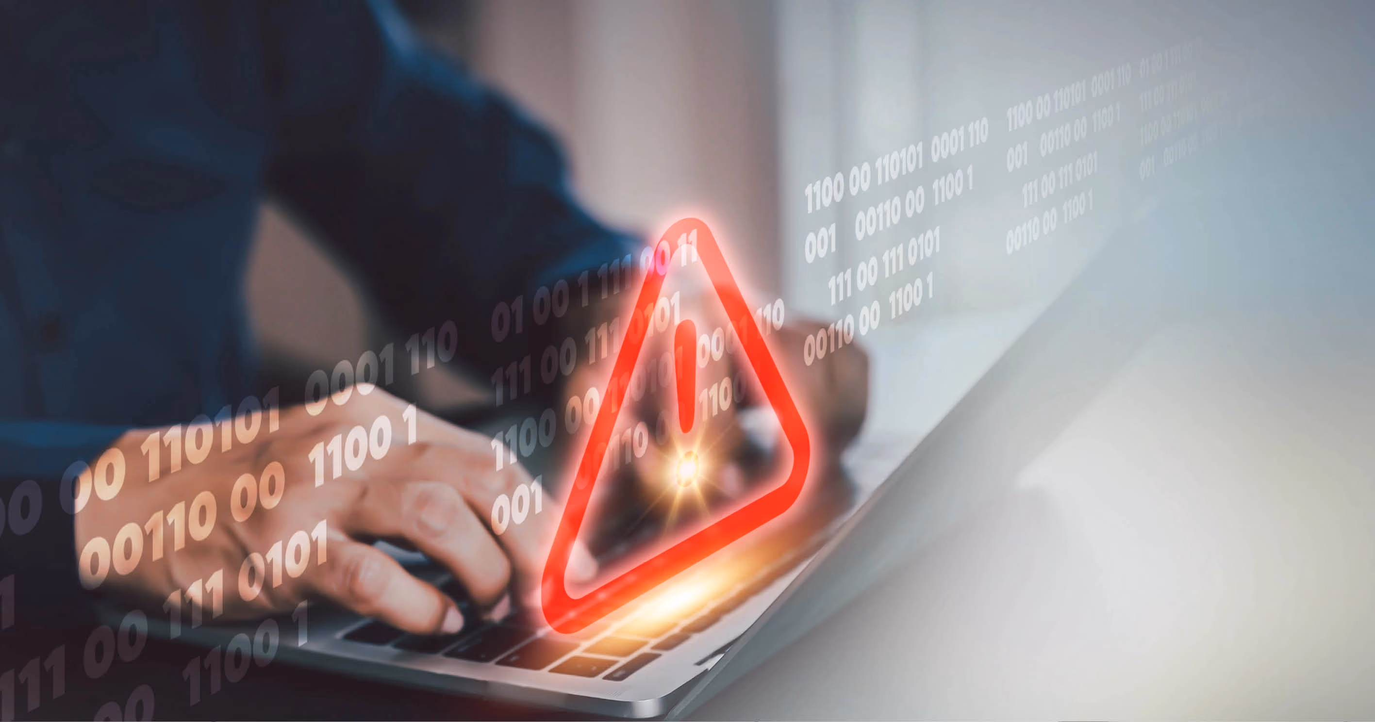 A person's hands typing on a laptop keyboard with a red warning triangle superimposed on top